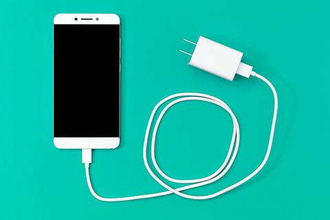 Directamente arriba del teléfono inteligente y el cargador de fondo turquesa