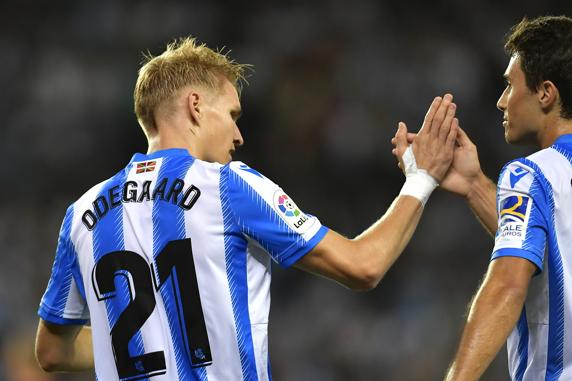 Odegaard choca la mano de un compañero con Guevara como testigo tras uno de los goles del encuentro ante el Alavés