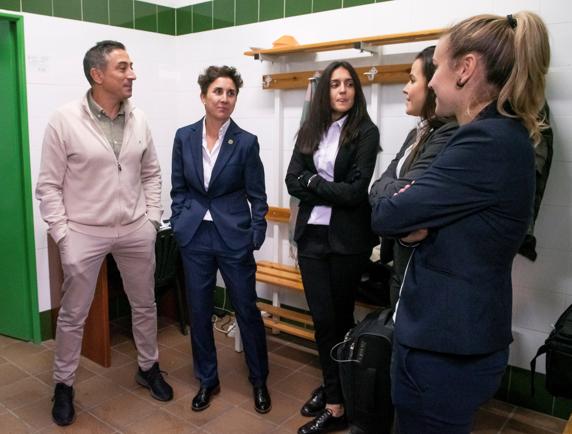 El entrenador del Real Betis Féminas, Antonio Contreras (i), conversa con el equipo arbitral tras la no presentación de los equipos, el Real Betis Féminas y el Sevilla
