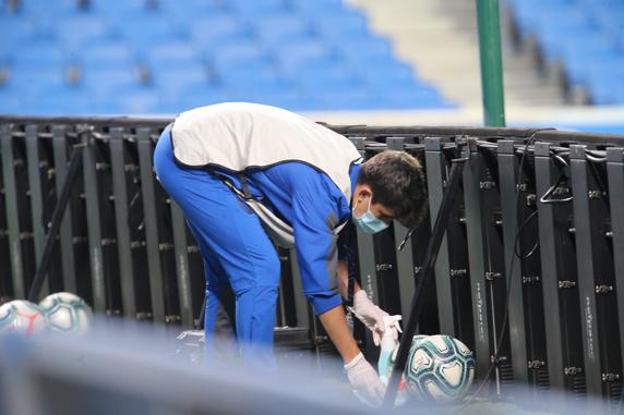 Uno de los cuatro recogepelotas desinfecta el balón