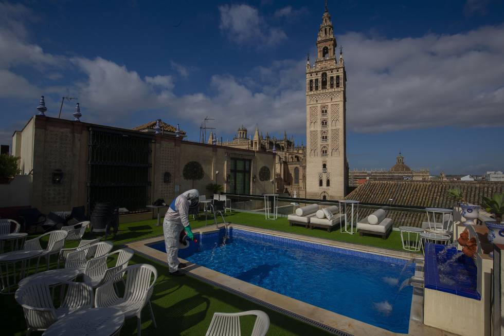 Un trabajador desinfecta la piscina con vistas a la Giralda del hotel Doña María, en Sevilla.