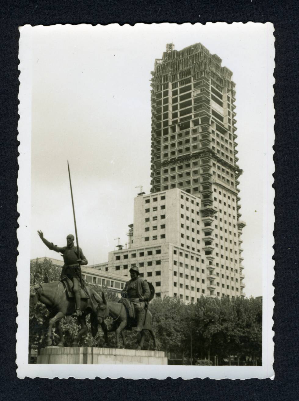 La Torre de Madrid en Construcción, con las esculturas de Don Quijote y Sancho en primer plano.