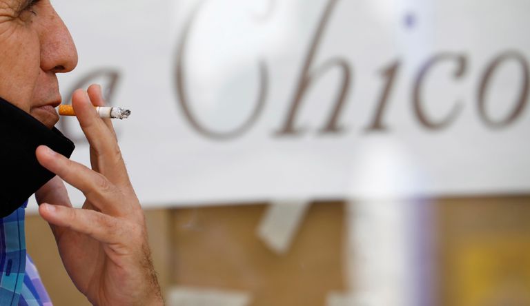 Un hombre fuma en la calle.