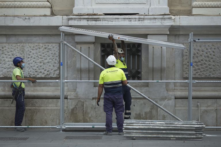 Varios operarios montan un andamio en un edificio del centro de Sevilla.