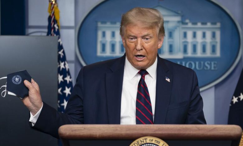 Donald Trump muestra una mascarilla durante una rueda de prensa en la Casa Blanca.