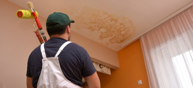 Hombre preparándose para pintar sobre una mancha de agua en el techo