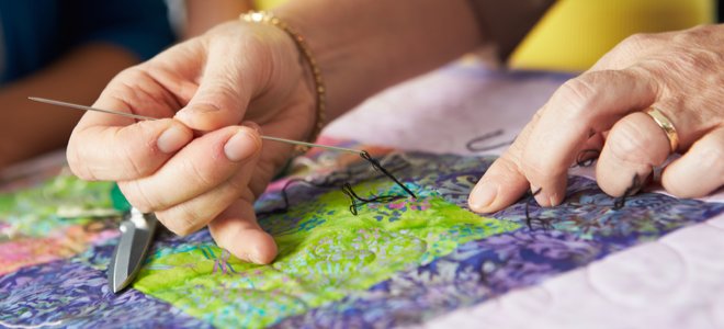 manos cosiendo un diseño colorido