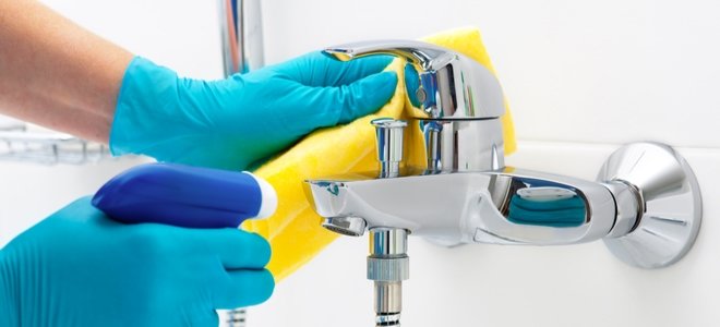 manos enguantadas limpiando un grifo de metal brillante