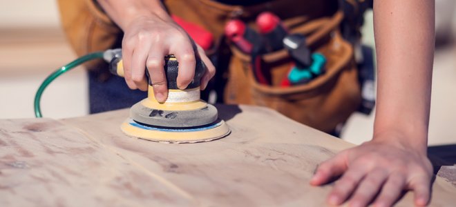 Mujer usando una lijadora en un trozo de madera