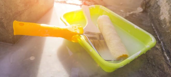 rodillo de pintura, brocha y bandeja con luz cálida