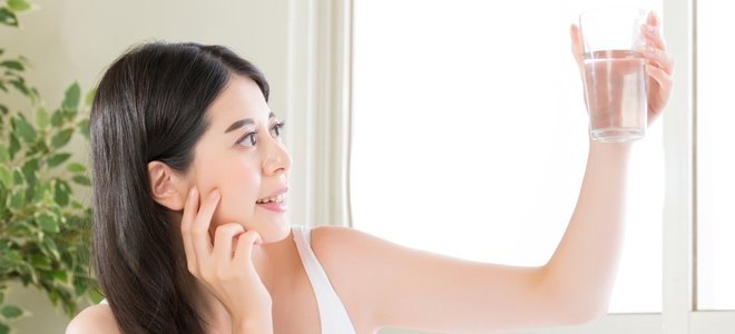 Mujer mirando un vaso de agua