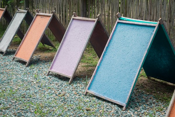 Una fila de marcos de madera con papel hecho en casa en ellos secando contra una valla.