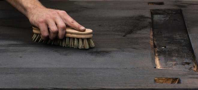 mano cepillando un trozo de madera carbonizada