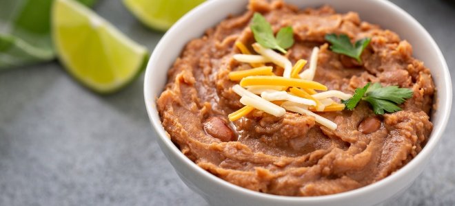 frijoles refritos en un bol con queso de lima y perejil