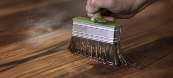 Mano con pincel aplicando acabado a la madera