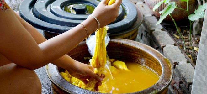 manos escurriendo tela en tinte amarillo natural