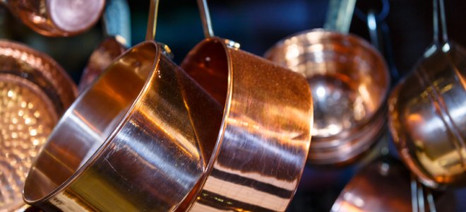 ollas y sartenes de cobre colgando de un estante de techo