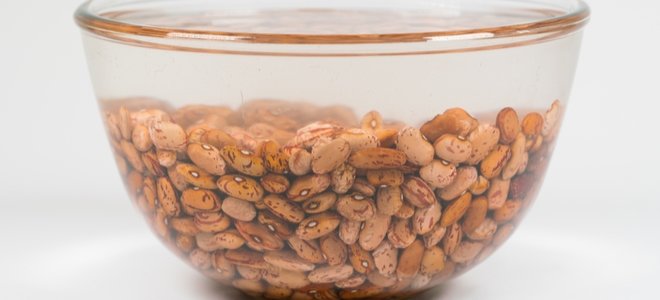 frijoles secos remojando en un recipiente con agua