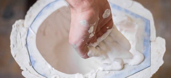 Mano sacando yeso de París de un balde