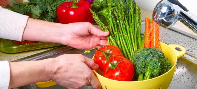 lavar un colador lleno de verduras en el fregadero