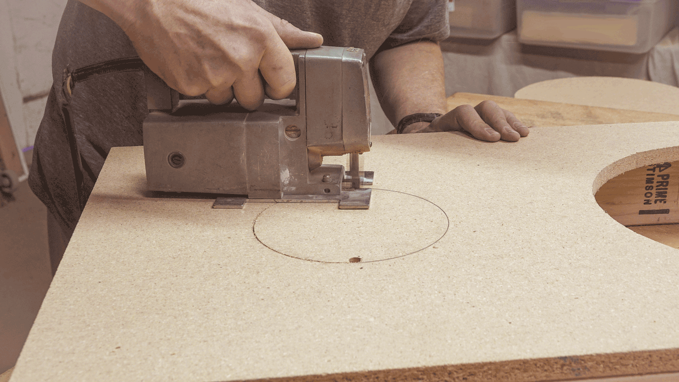 Sierra de cerradura cortando círculo de cornhole en aglomerado