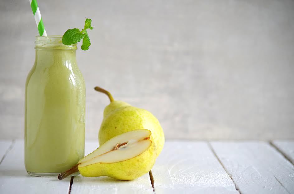 Un batido verde con peras al lado. 