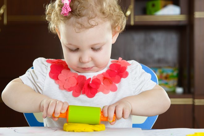 Una niña rueda plastilina.