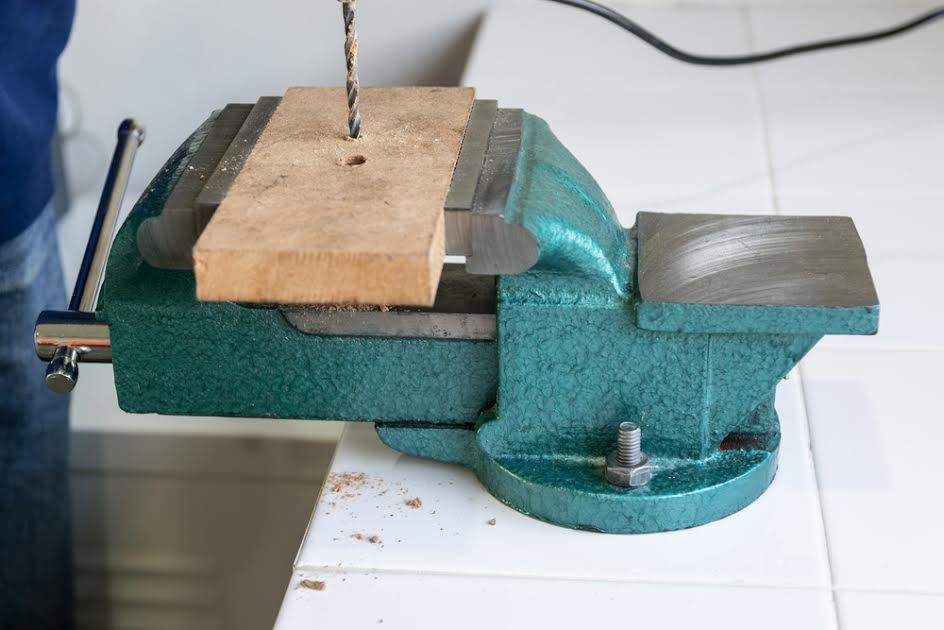 Un tornillo de banco con un trozo de madera.