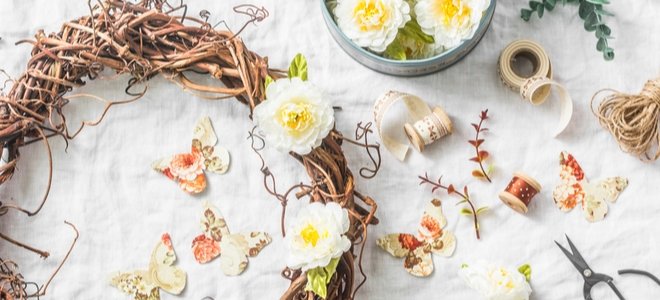 una corona de vid sobre una mesa con hilo y rosas amarillas claras