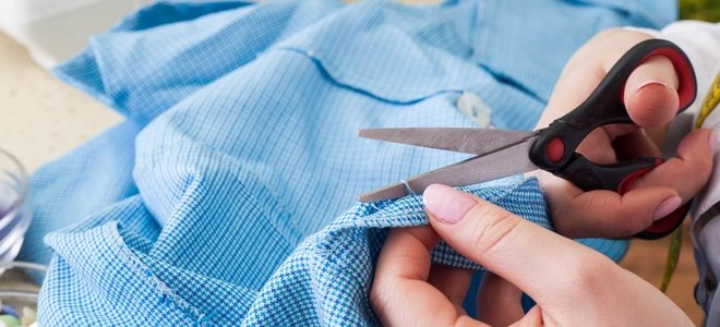 manos cortando tela azul con tijeras