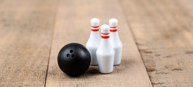 Bolas de boliche en miniatura y pasador sobre superficie de madera