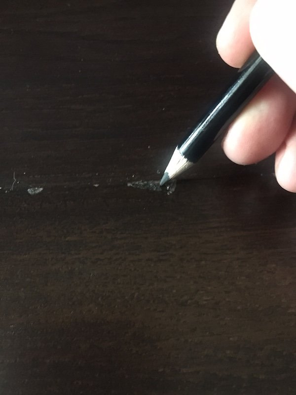 Un lápiz que marca un rasguño en la madera. 