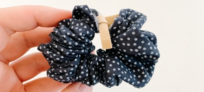 dedos sosteniendo scrunchie de lunares con banda elástica