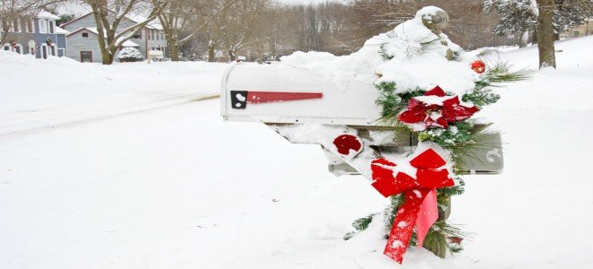 Un buzón en la nieve decorado para Navidad con lazos y guirnaldas. 