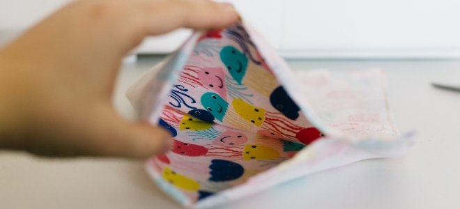 Mano que abre la almohadilla térmica de tela casera con diseño colorido doblado abierto