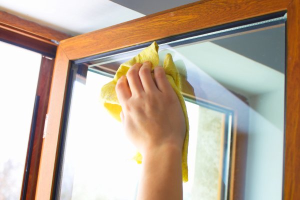 Una mano sosteniendo un trapo limpiando una ventana. 