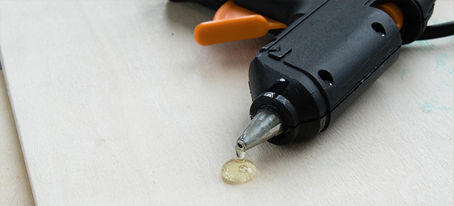 Pistola de pegamento caliente con pegamento goteando sobre papel