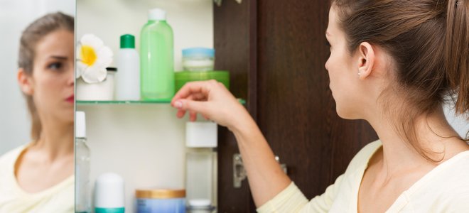 mujer abriendo el armario con espejo del baño