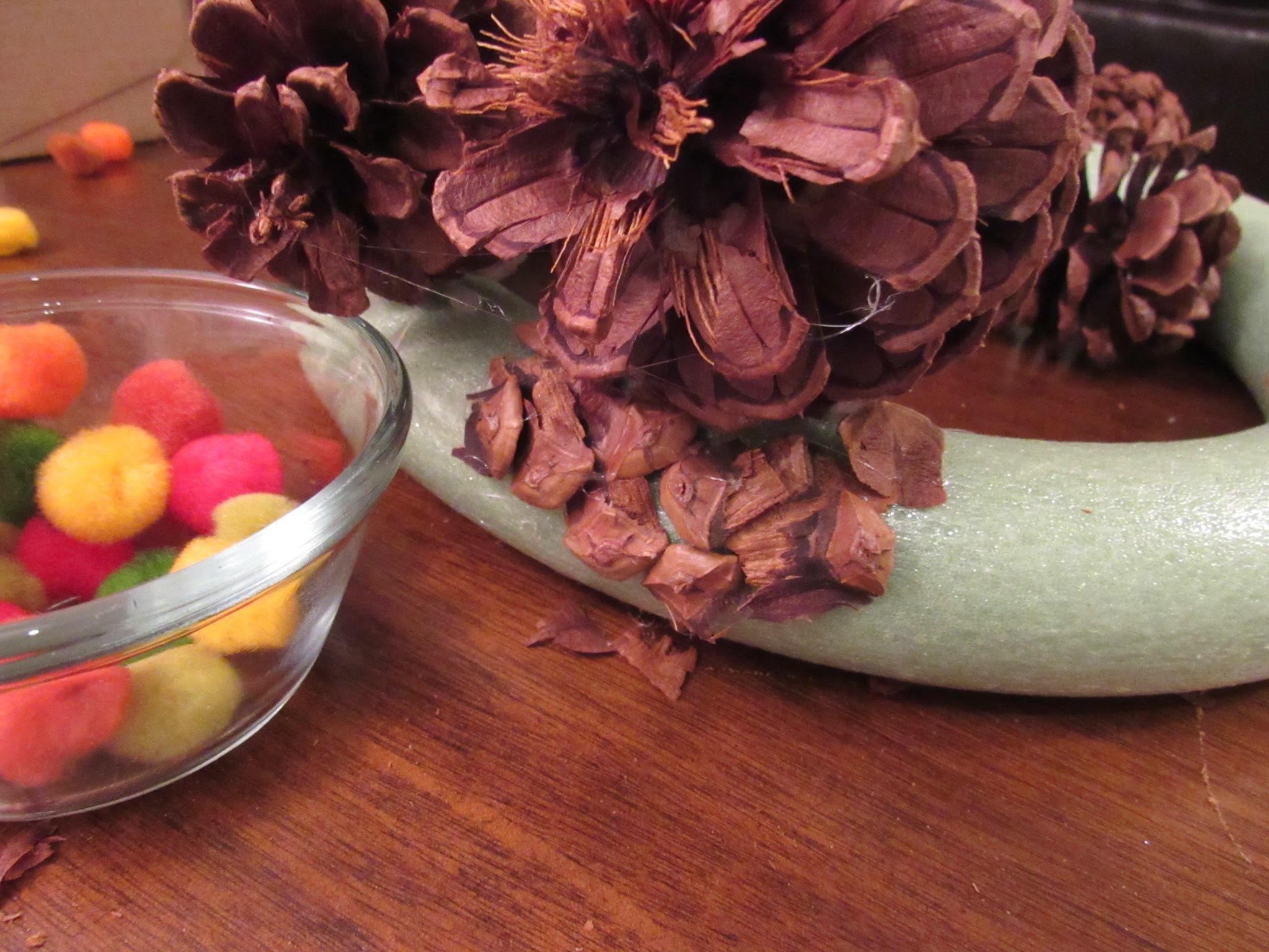 Conos de pino pegados en forma de corona de espuma.