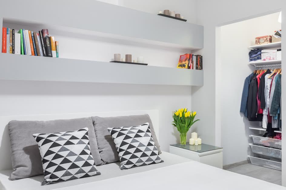 Un dormitorio con estantes de almacenamiento encima de la cama. 