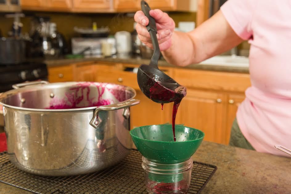 Una mujer canalizando conservas en un frasco de vidrio.