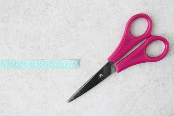 Un par de tijeras de mango rosa y un corte de cinta azul. 