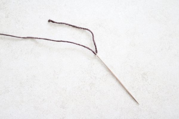 Enhebrar el cordón a través de una aguja. 