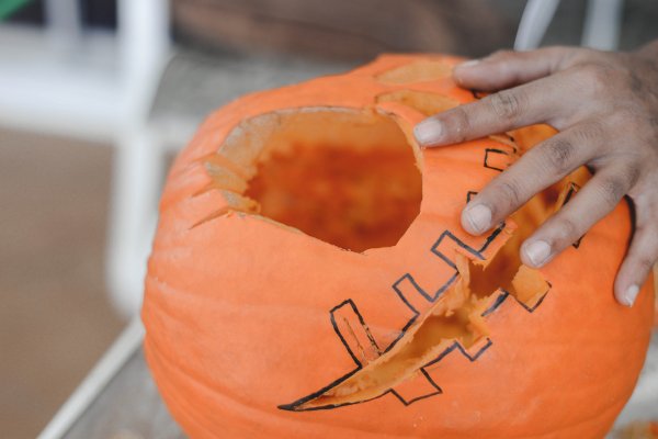 Una mano tallando un jack o 'lantern. 