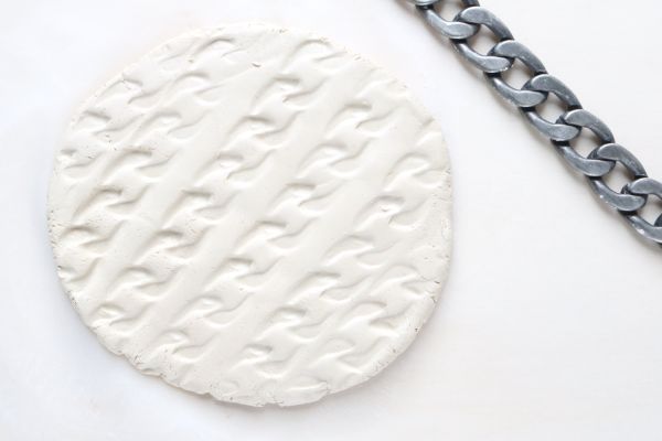 Un pedazo de arcilla con una pulsera de plata al lado. 