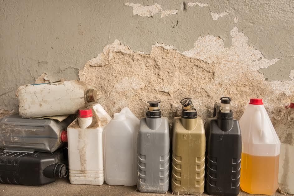 Una hilera de productos químicos embotellados contra una pared. 