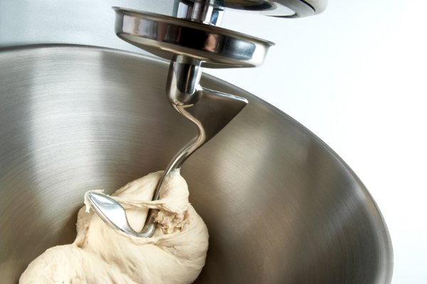 Un tazón de batidora de acero inoxidable con masa de pan. 