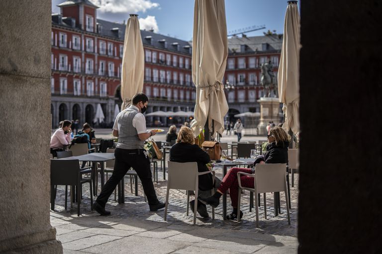 Un camarero atiende a unas clientas en la plaza Mayor de Madrid, este lunes.