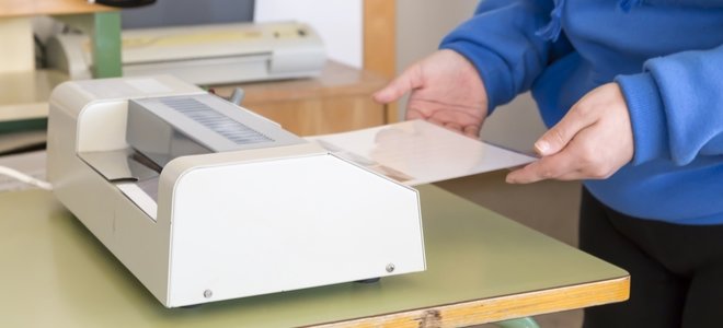manos alimentando un papel en una máquina laminadora