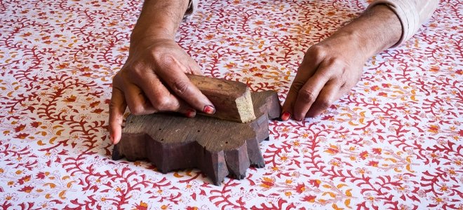 manos colocando un sello de impresión en tela de intrincado diseño